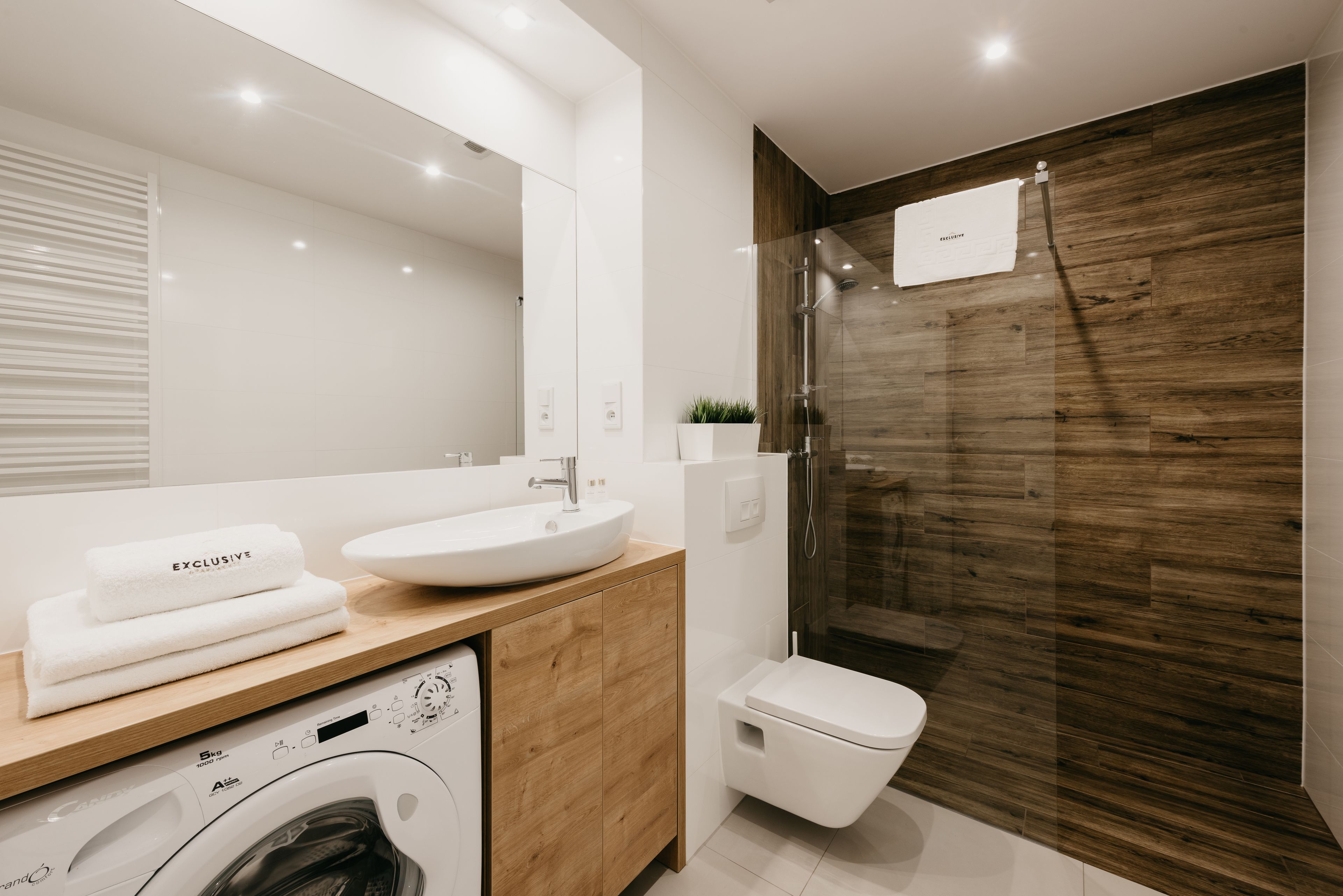 A modern bathroom with a wooden vanity, a sink, a toilet, and a glass shower enclosure.