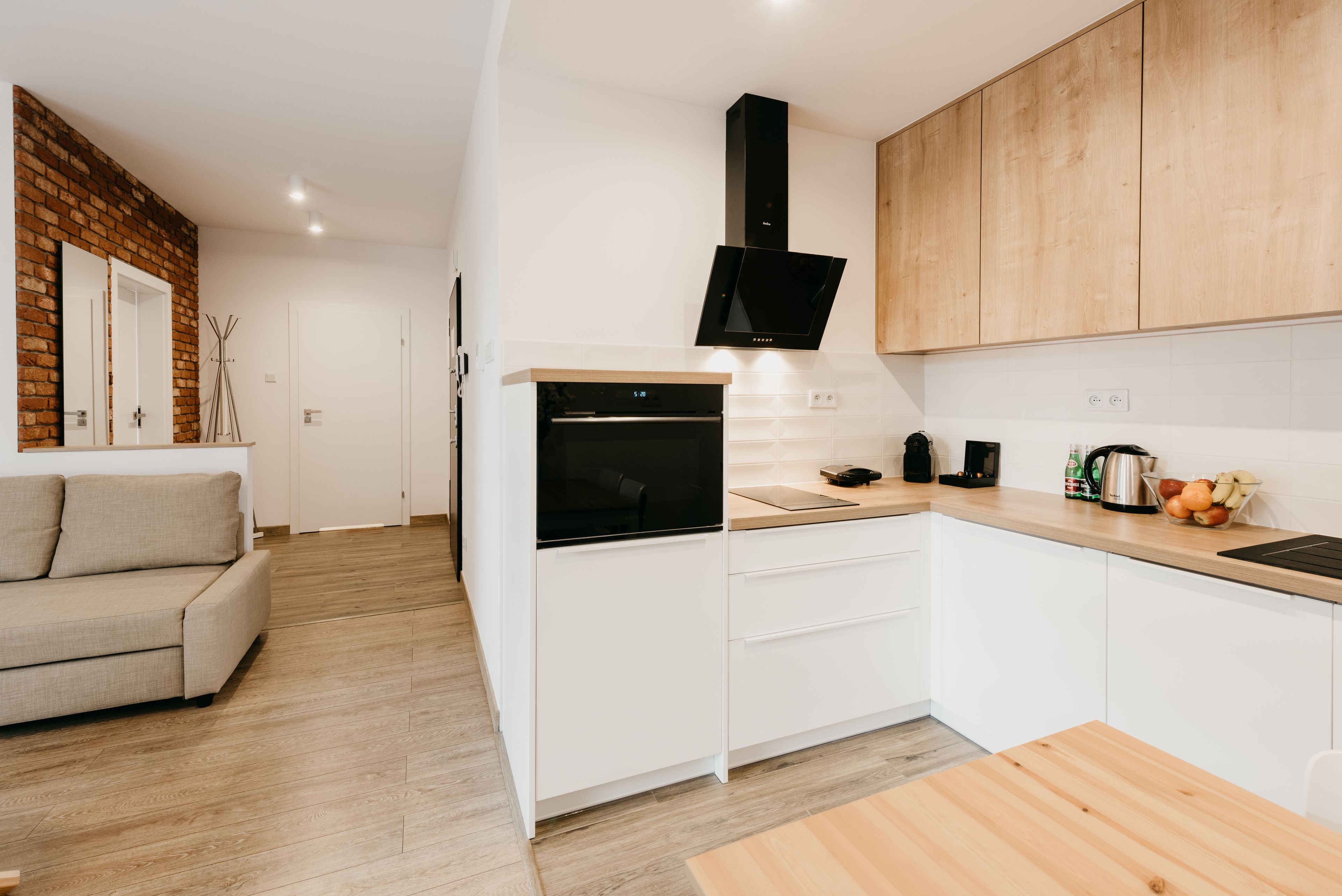 A modern kitchen with white cabinetry, a built-in oven, and a wooden countertop.