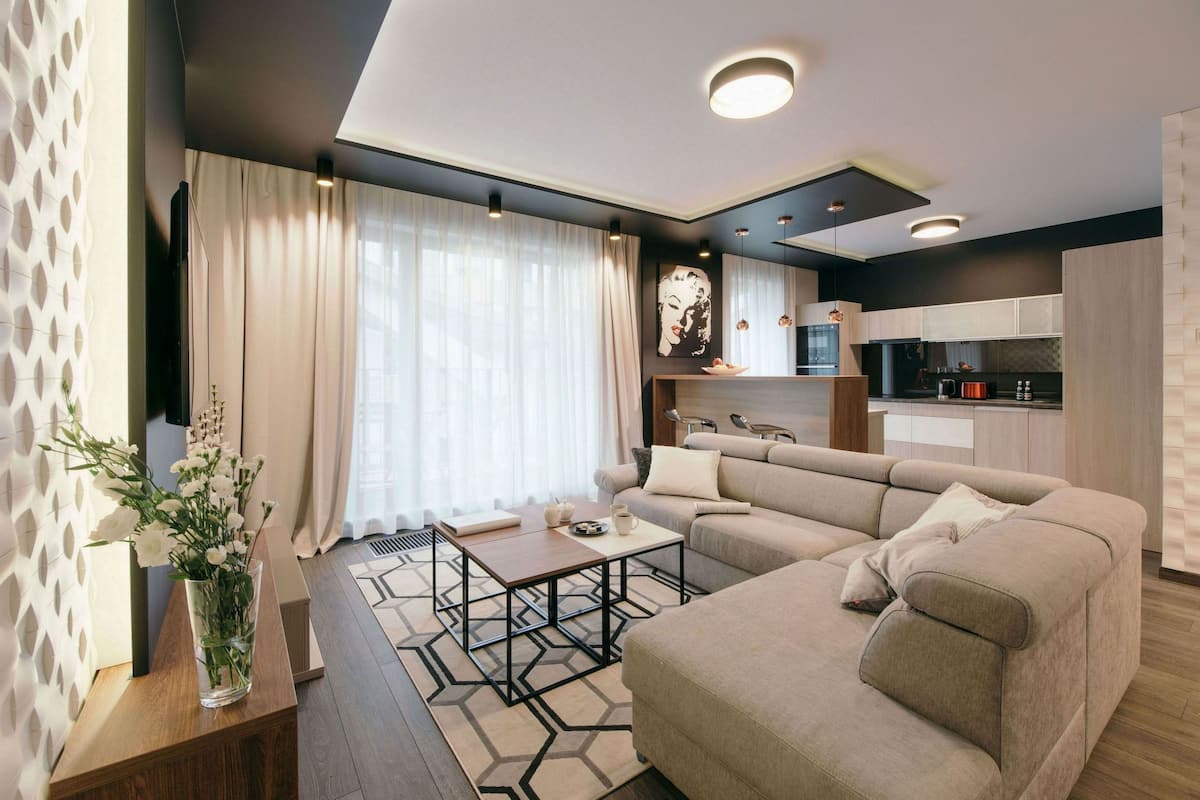 A modern living room with a sofa, coffee table, and a vase of flowers.