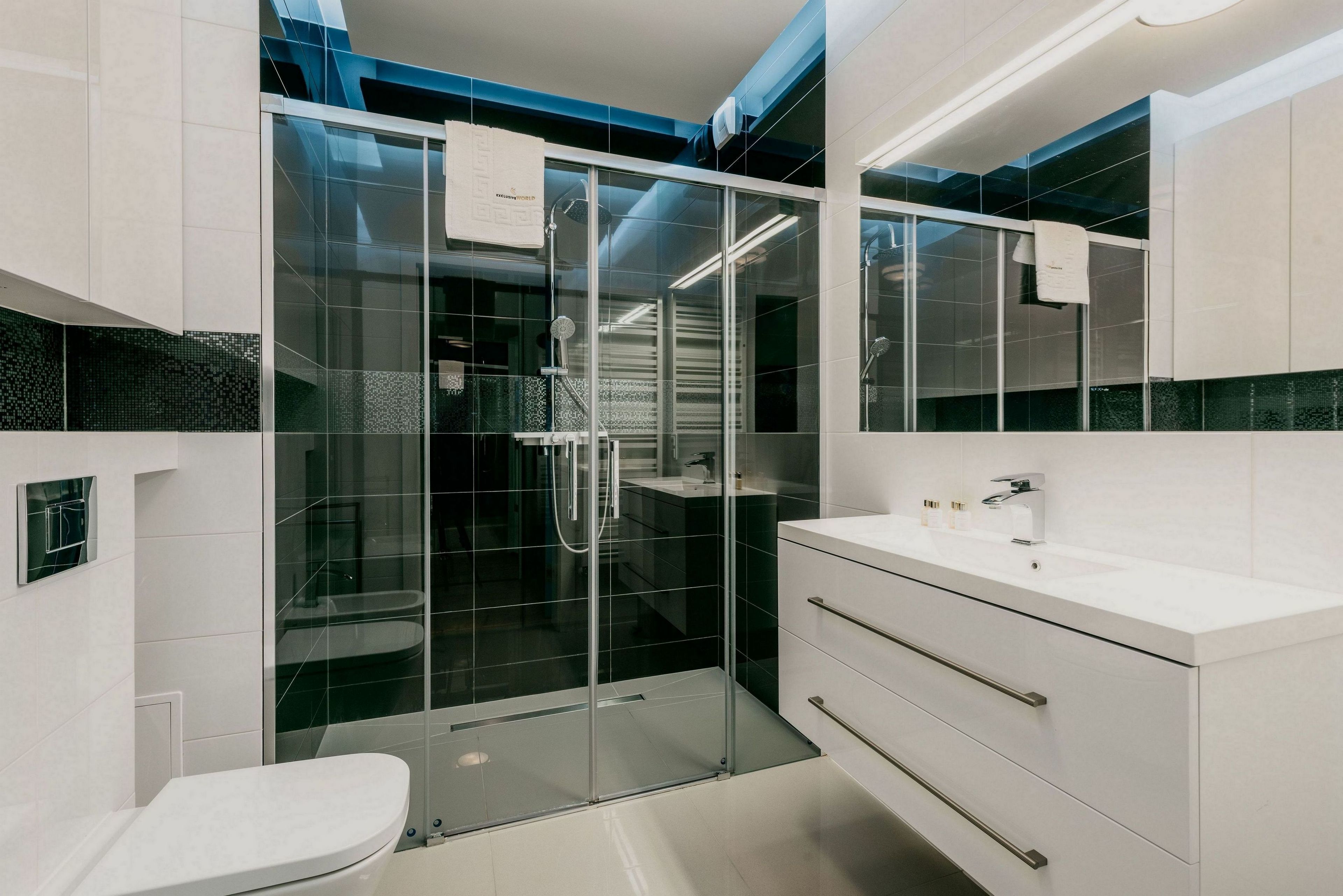 A modern bathroom with a glass shower enclosure, a white sink, and a large mirror.