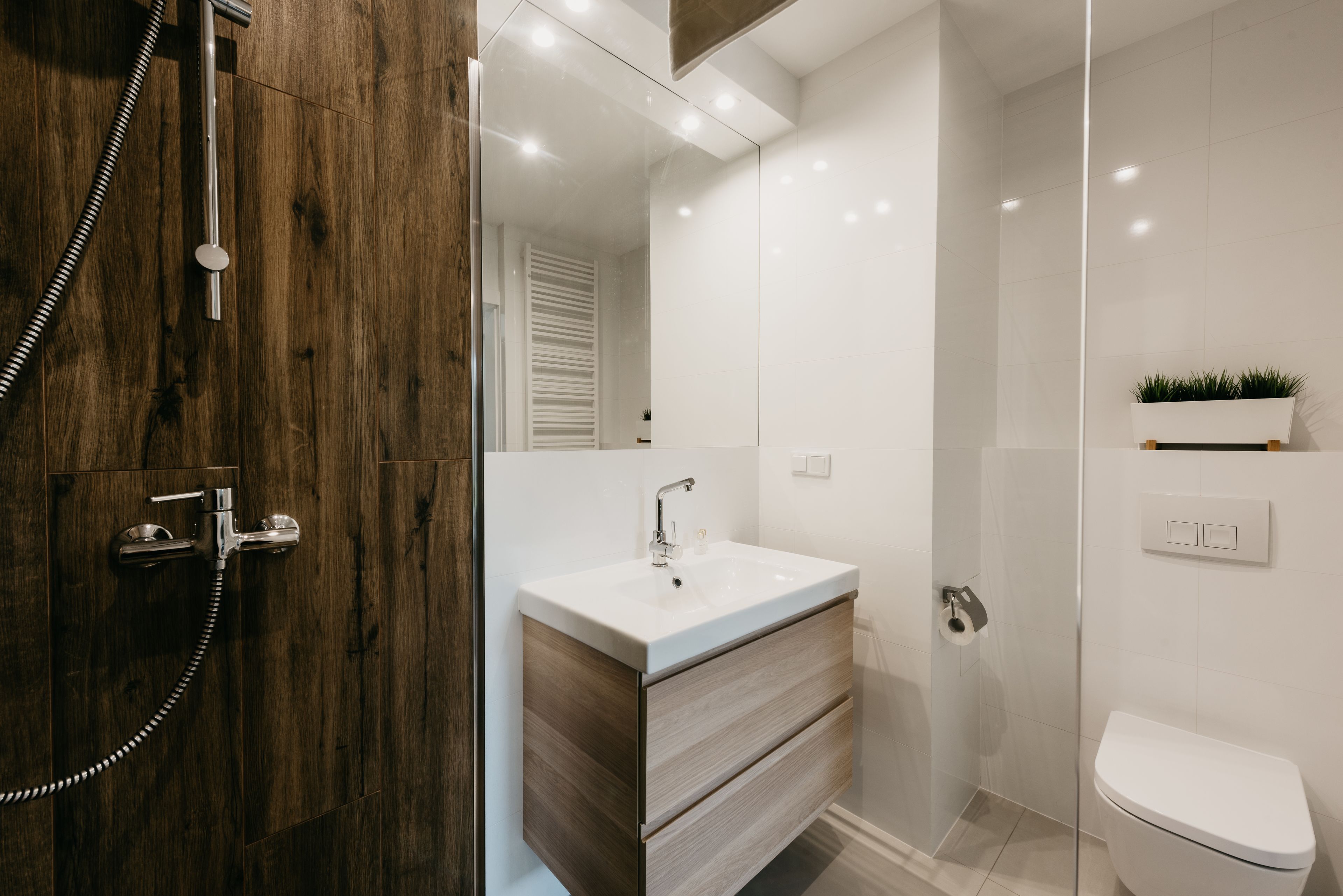 A modern bathroom with a wooden vanity, a glass shower enclosure, and a white toilet.