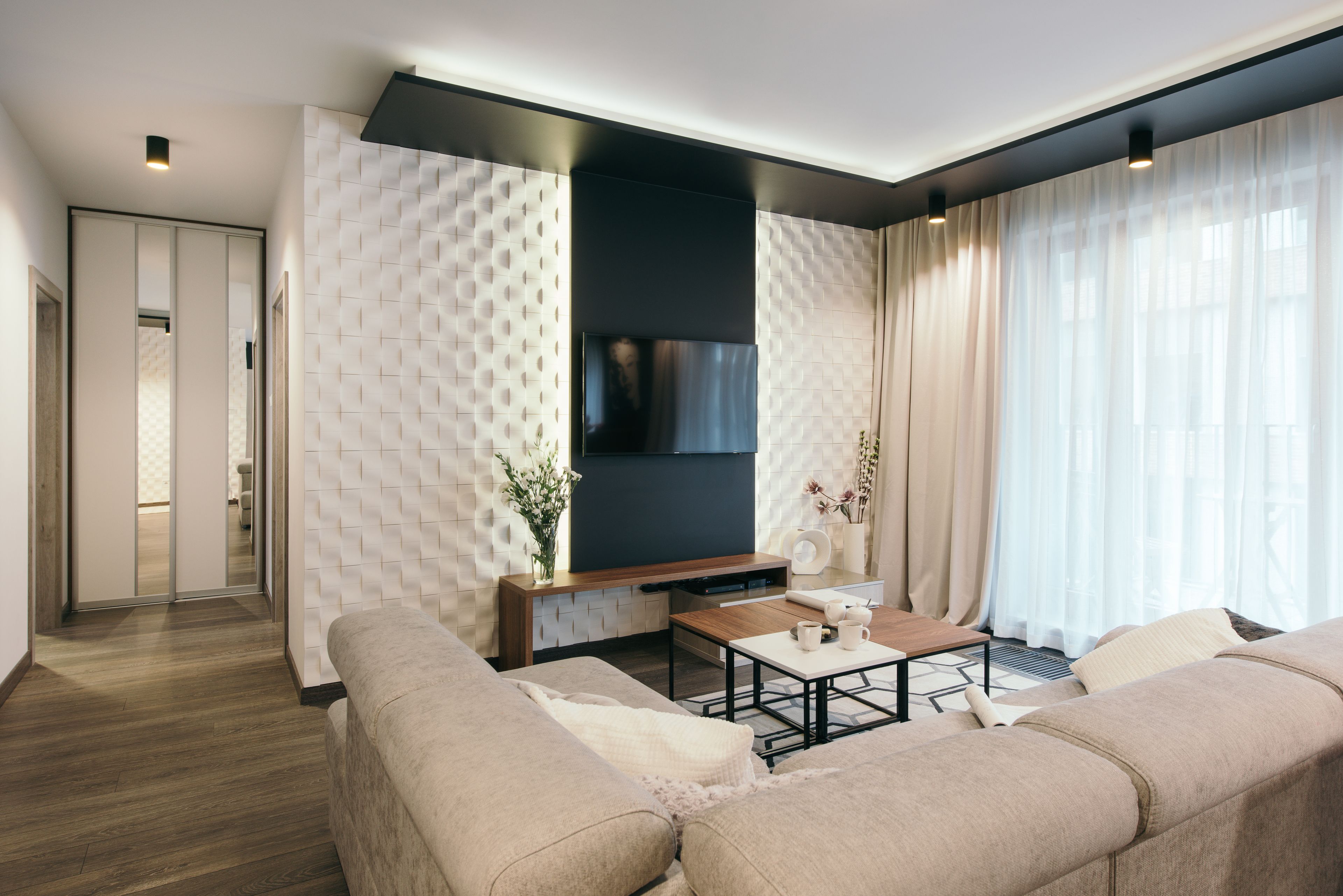 A modern living room with a sofa, coffee table, and a flat-screen TV mounted on the wall.