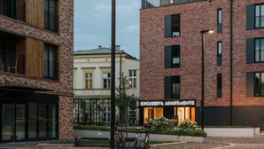 A modern building with a brick facade, a sign reading "EXCLUSIVE APARTMENTS," and a courtyard with bicycles. - Exclusive Apartments | Krakow Lubicz Brewery (Kraków)