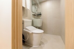 A modern bathroom with a toilet, bidet, and a mirror above the sink. - Hotel Marguerite (Seoul)