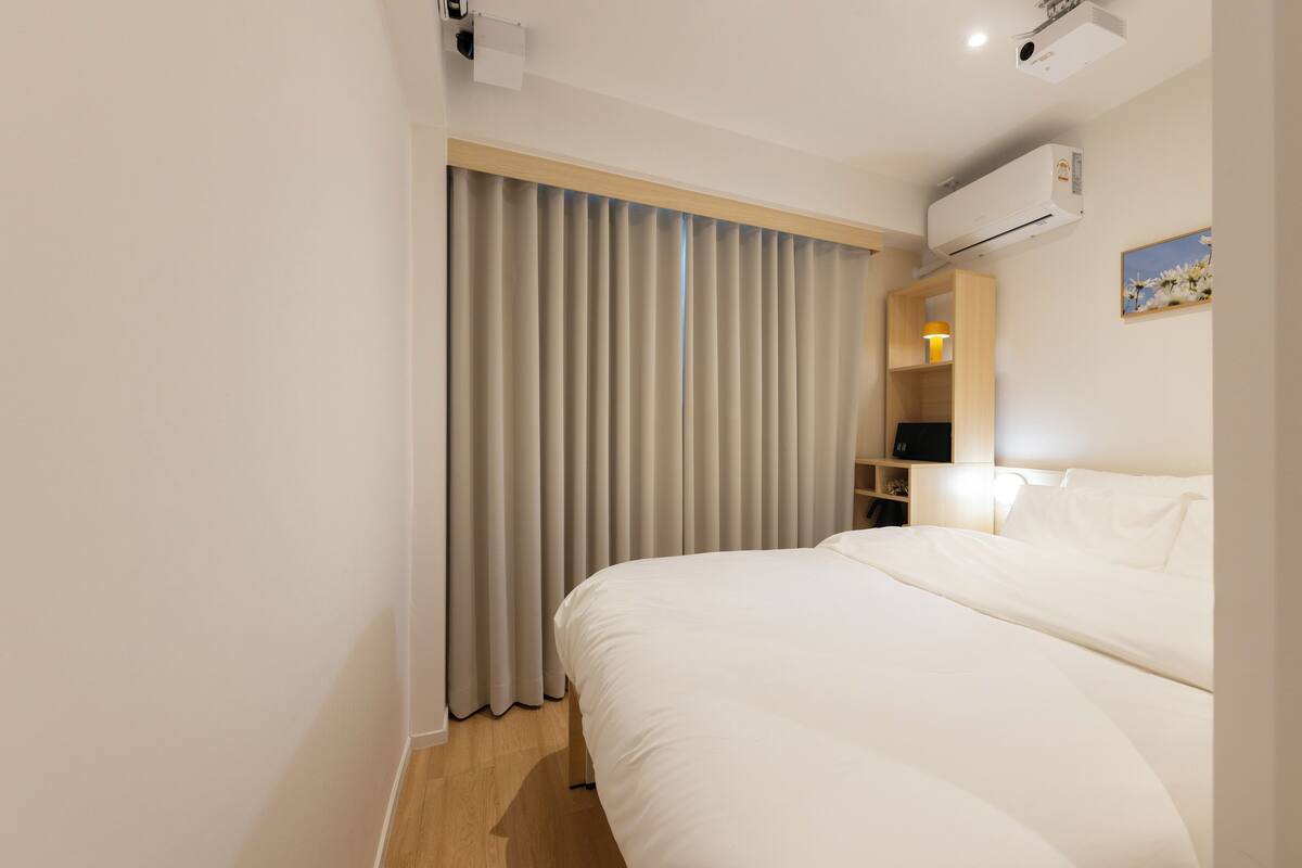 Une chambre d’hôtel avec un grand lit, une armoire, un bureau et une fenêtre avec des rideaux.