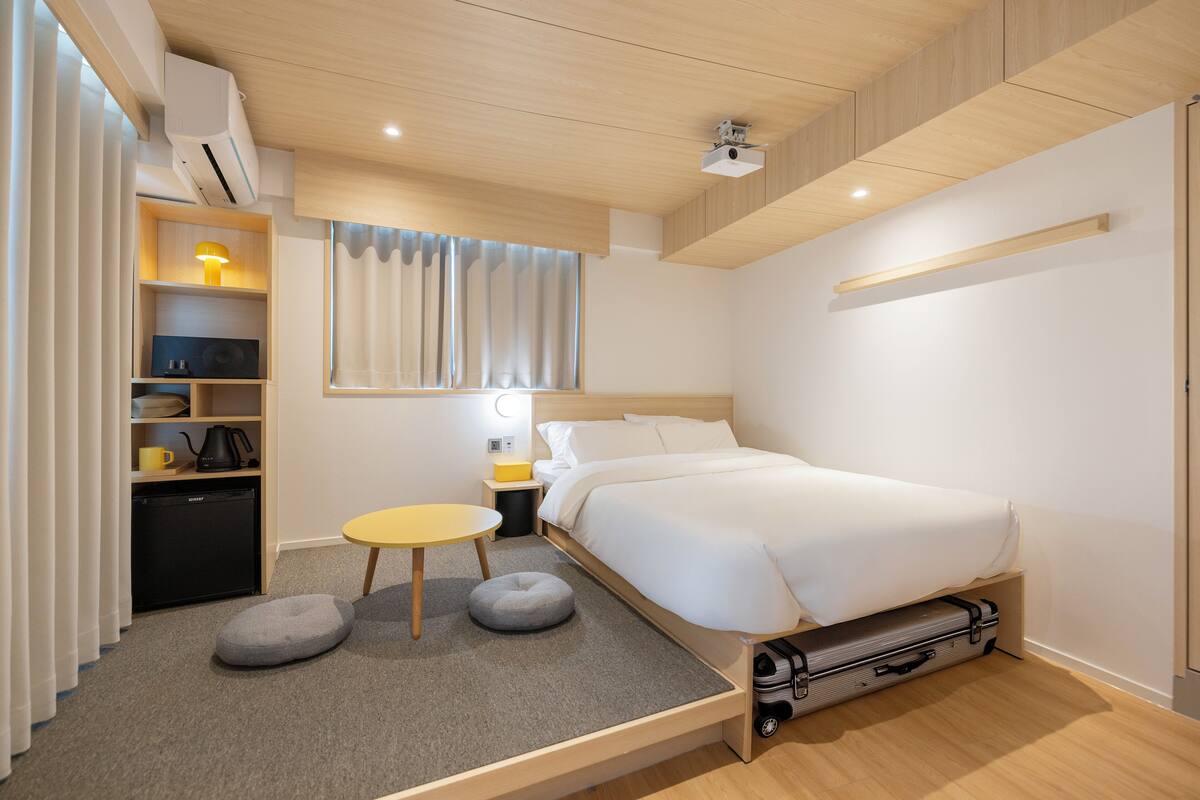 Une chambre moderne comprenant un lit, une table de chevet, une lampe et un petit coin salon.