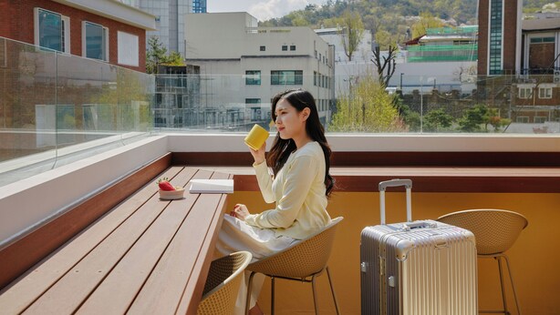 Une femme assise sur un balcon, d’où l’on peut admirer des immeubles et une pagode.