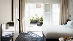 Habitación de hotel con una cama grande, televisión, escritorio y vista al jardín exterior.