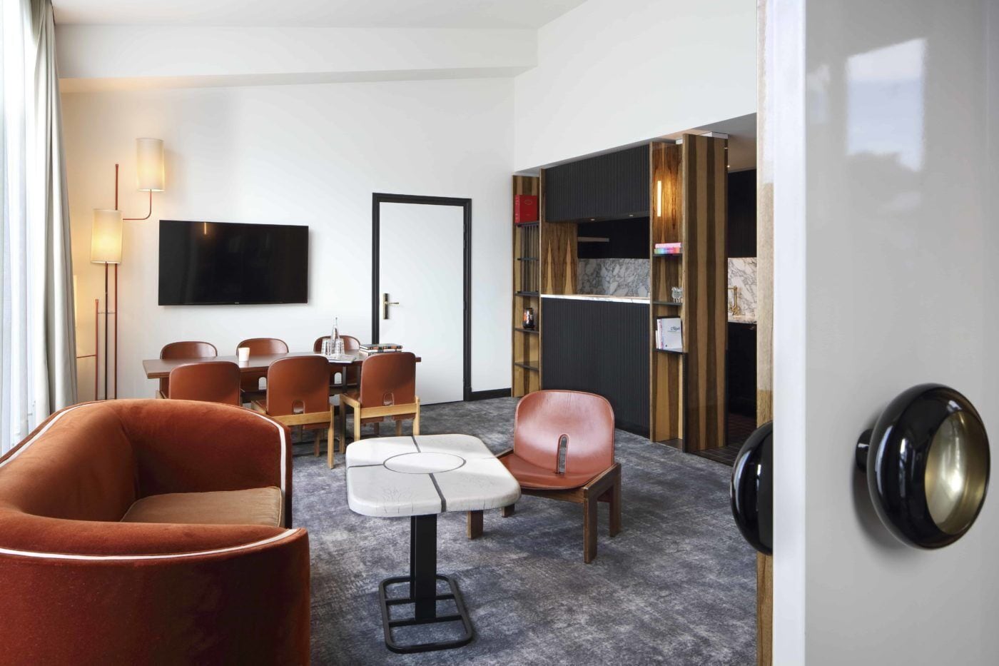 Une chambre d’hôtel équipée d’un téléviseur à écran plat, d’une table à manger avec des chaises, d’un canapé et d’une petite table avec une chaise.