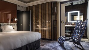 Habitación de hotel con cama, una silla, armario y tocador con espejo.