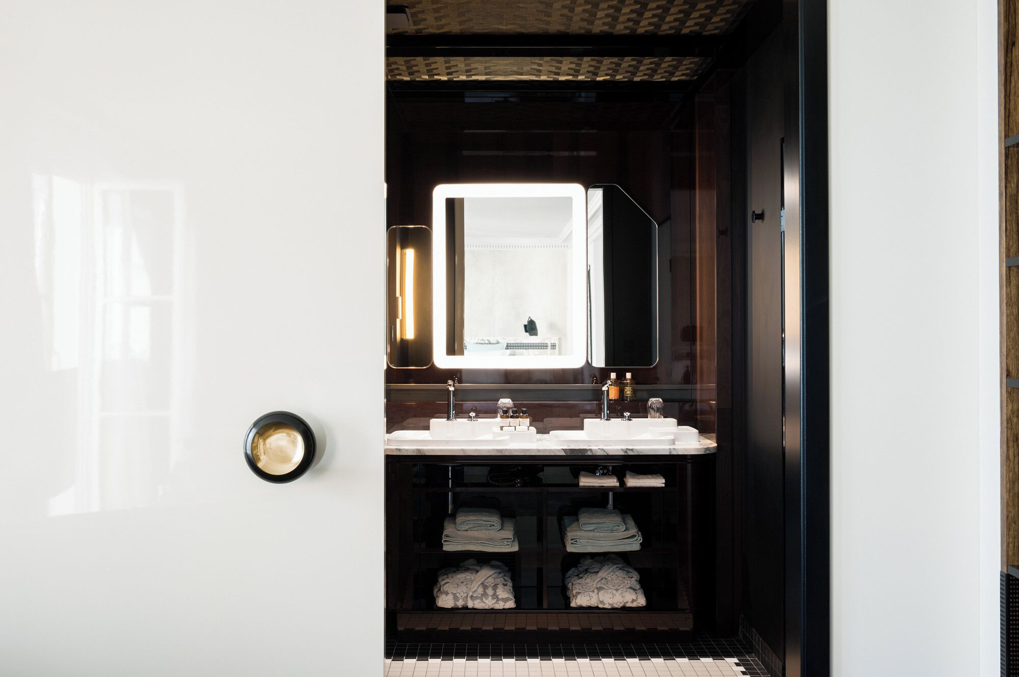 Une salle de bain moderne avec un grand miroir, deux lavabos et un porte-serviettes.
