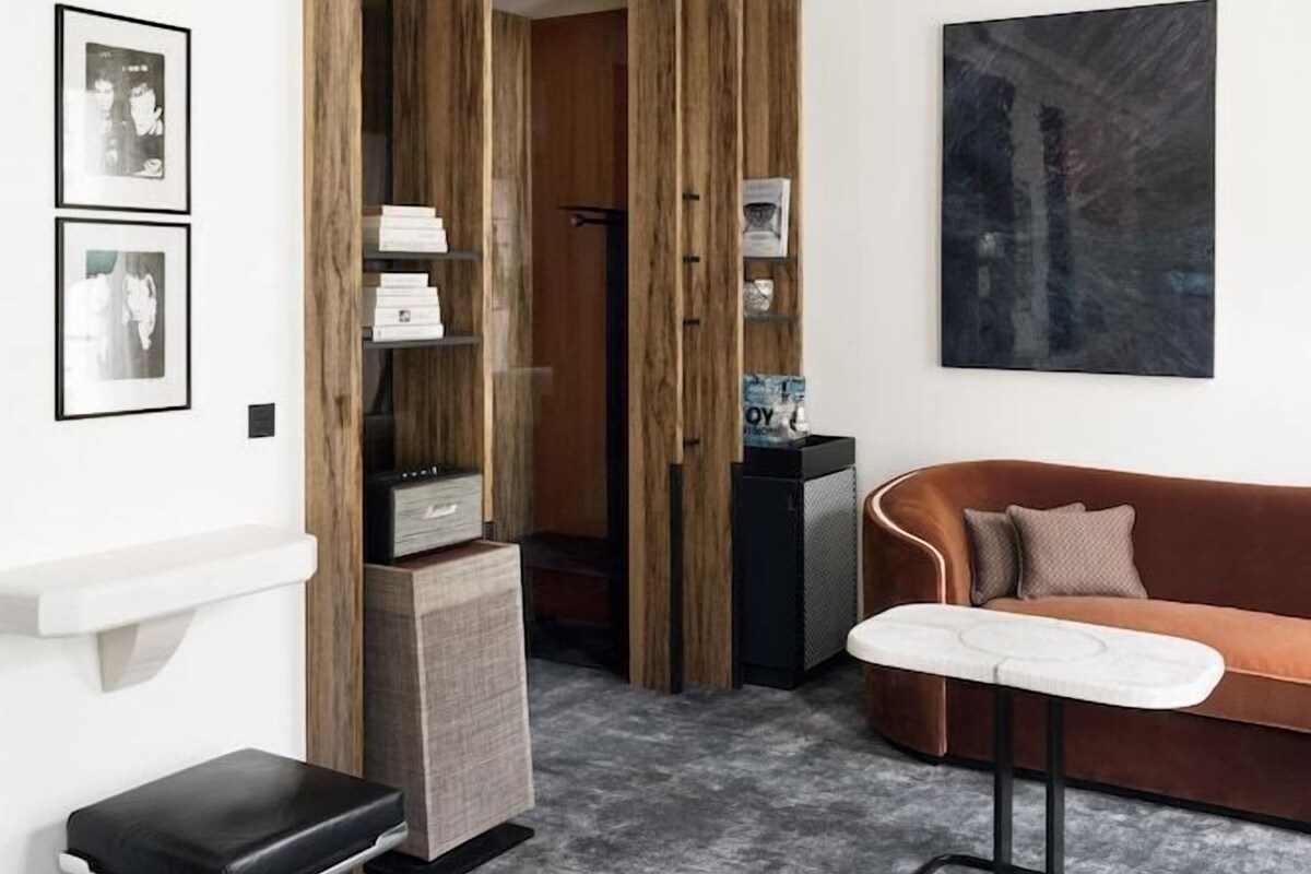 A modern living room with a sofa, a coffee table, a black bench, and a wooden bookshelf.