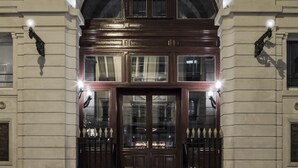 Fachada de un edificio con un letrero que dice "BAINS" sobre un imponente arco de entrada.