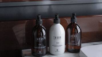 Una encimera de baño con tres botellas de champú y acondicionador Terre Mars.