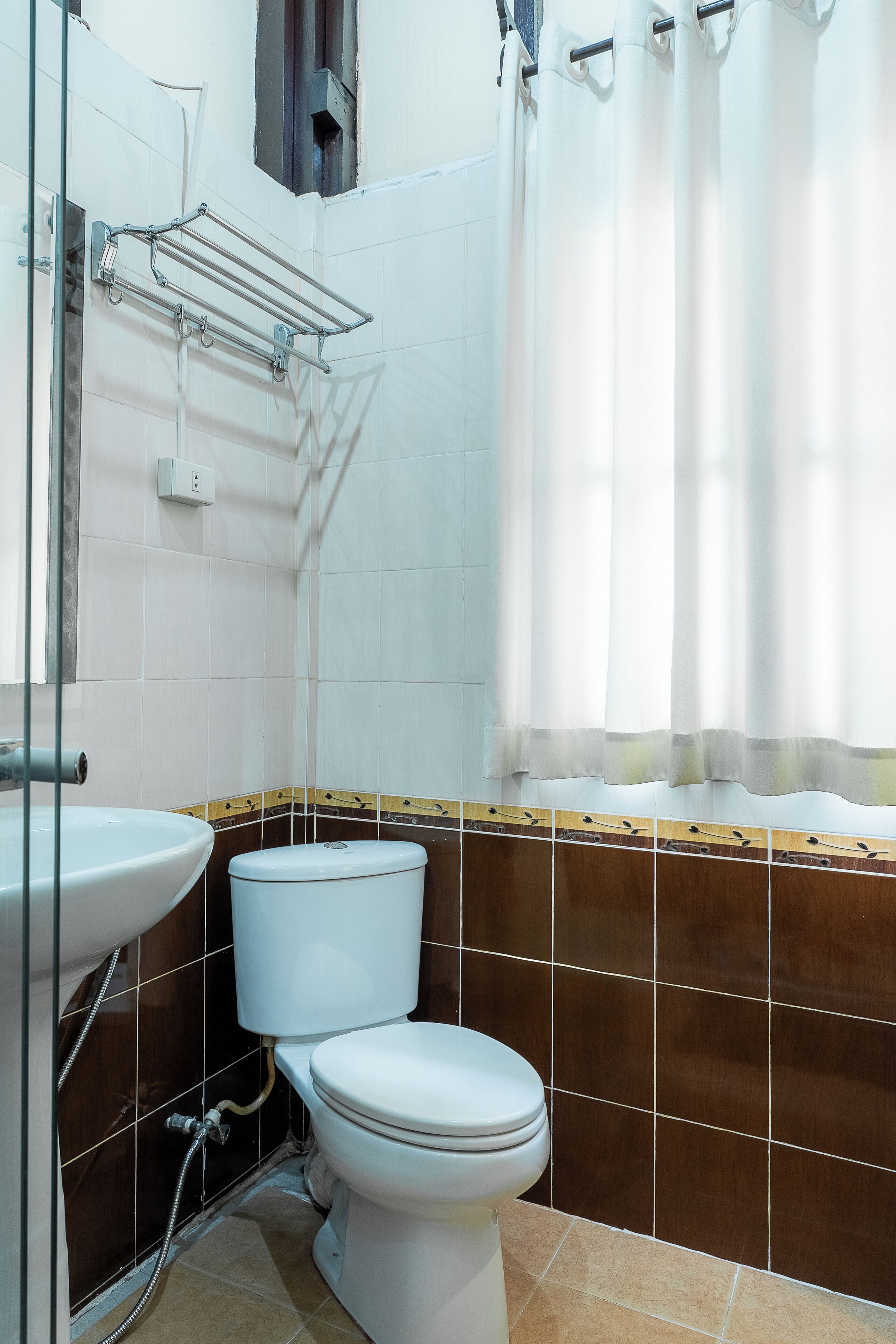 Baño con inodoro, lavamanos, cortina de ducha y toallero.