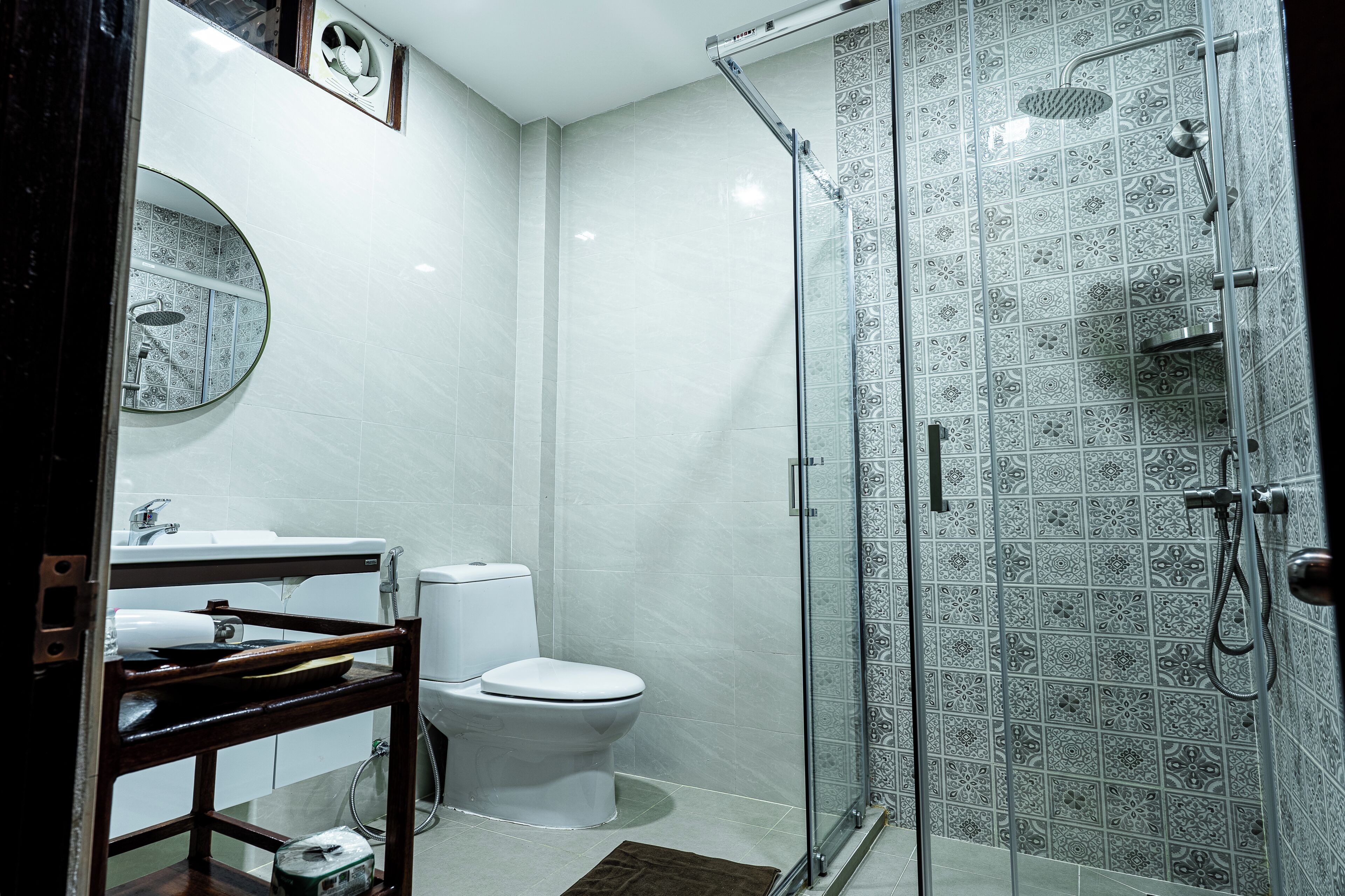 A bathroom with a toilet, sink, and shower with patterned tiles.