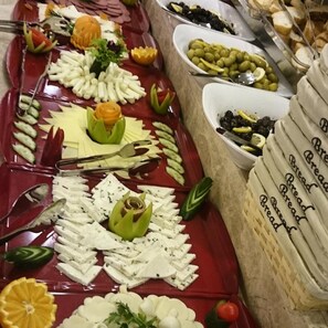 A buffet with various food items including bread, olives, and cheese.