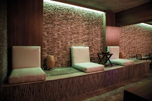 A spa area with cushioned seating, a stone wall, and a wooden reception desk.