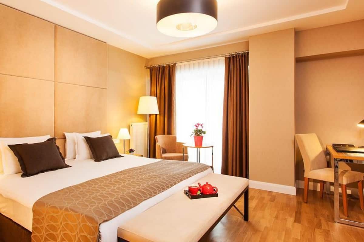 A hotel room with a large bed, bedside tables, a desk, and a chair.