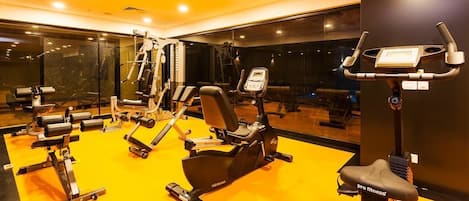 A gym with various exercise equipment, including a stationary bike, a rowing machine, and weight machines.