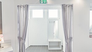 A bathroom with striped curtains, a white sink, and a shower area. - Tannenblick (Bad Vilbel)