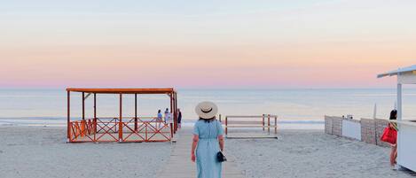 A wooden boardwalk leading to a beach with a wooden structure and a beach hut.