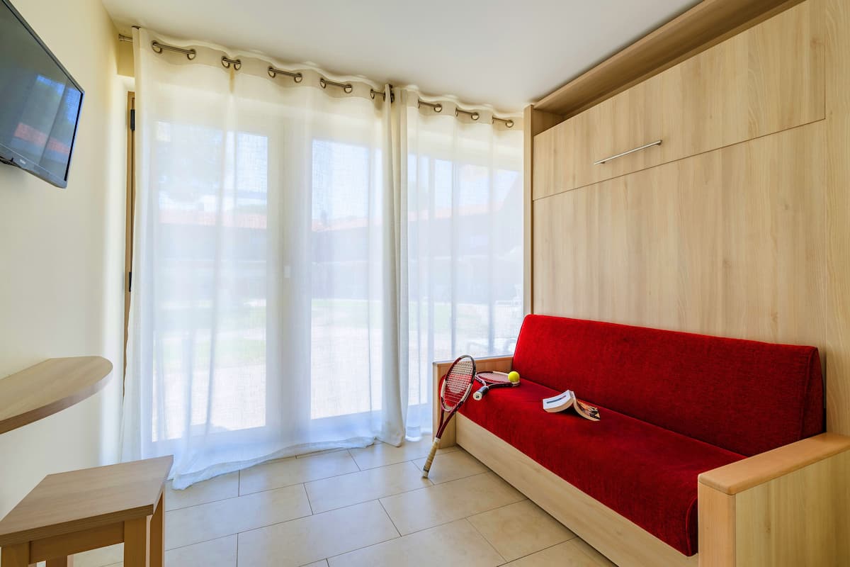 A room with a red sofa, a wooden TV stand, and a tennis racket on the floor.