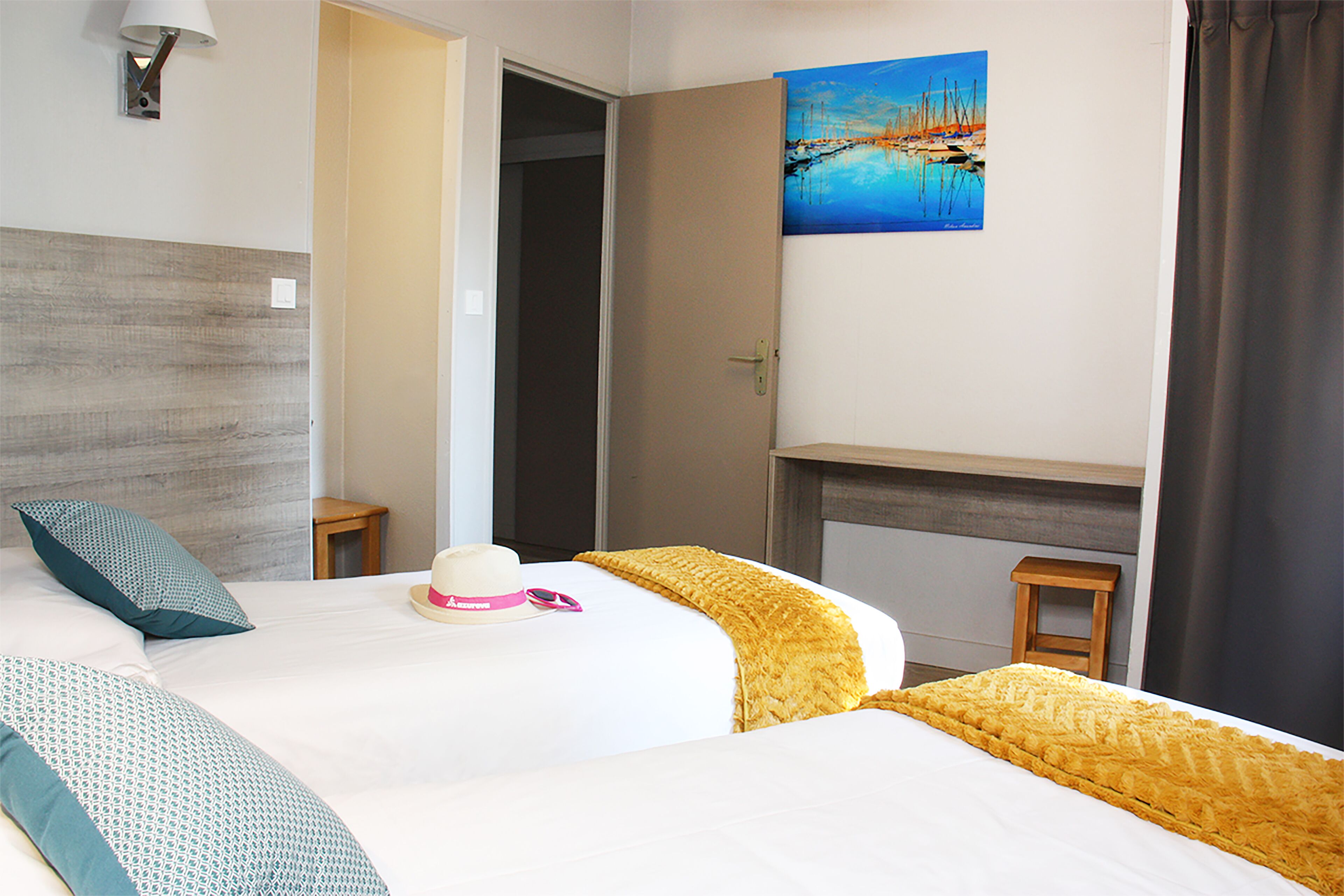 A hotel room with a large bed, a painting of a lake, a small table, and a lamp.
