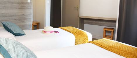A hotel room with a large bed, a painting of a lake, a small table, and a lamp.