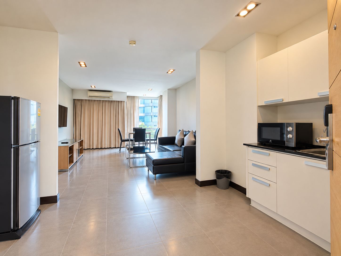 A modern kitchen with a microwave, a refrigerator, and a dining area with a table and chairs.
