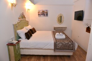 A neatly made bed with a quilted mattress, a bedside table with a telephone, and a wall-mounted mirror. - Oriella Hotel (Istanbul)