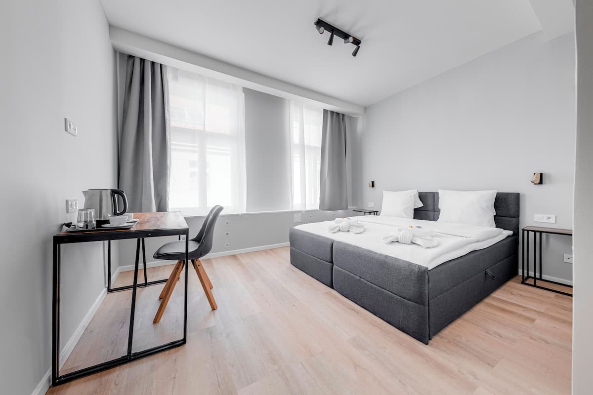 A modern hotel room with a bed, a desk, and a chair.
