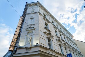 A corner of a building with ornate architectural details and a sign that reads "HOTEL". - Hotel Koruna (Prague)