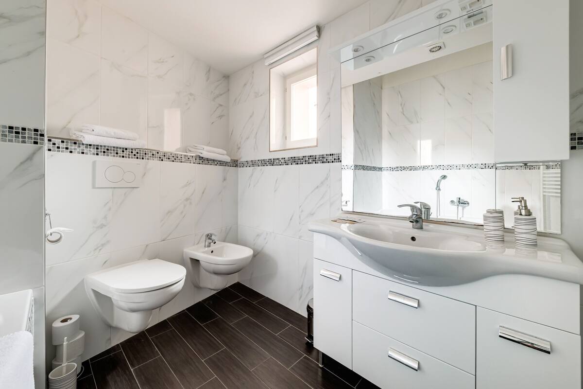 A modern bathroom with a white vanity, a bidet, and a toilet.