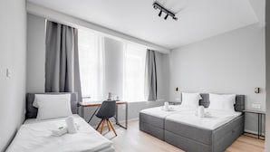 A modern hotel room with two beds, a desk, and a large window with curtains. - Hotel Koruna (Prague)