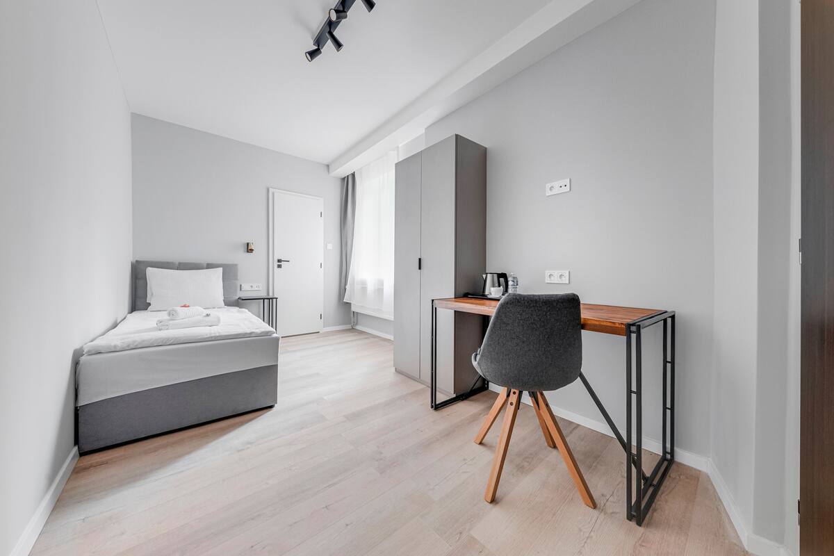 A modern bedroom with a bed, a desk, and a chair.