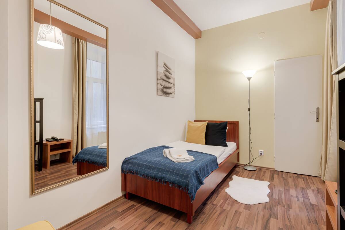 A bedroom with a wooden bed, a mirror, a bedside lamp, and a door.