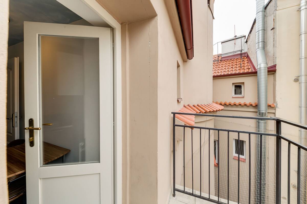 A narrow corridor with a white door, a wooden bench, and a metal railing.