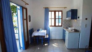 Una cocina compacta con una mesa y sillas, un refrigerador pequeño y una ventana con cortinas.