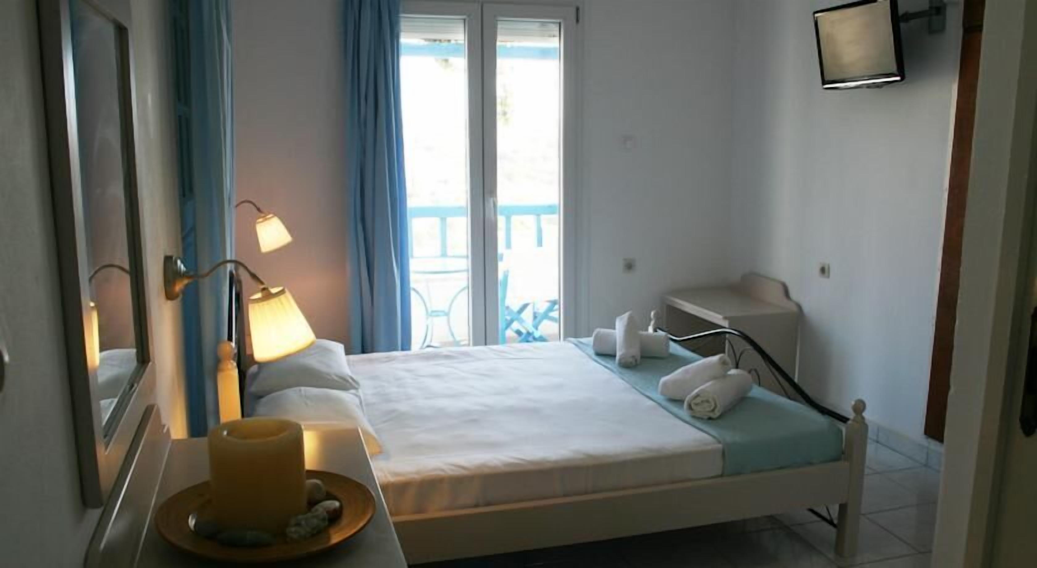 Une chambre à coucher avec un lit, des lampes de chevet, une table de chevet avec une tasse, et une vue sur le balcon extérieur.