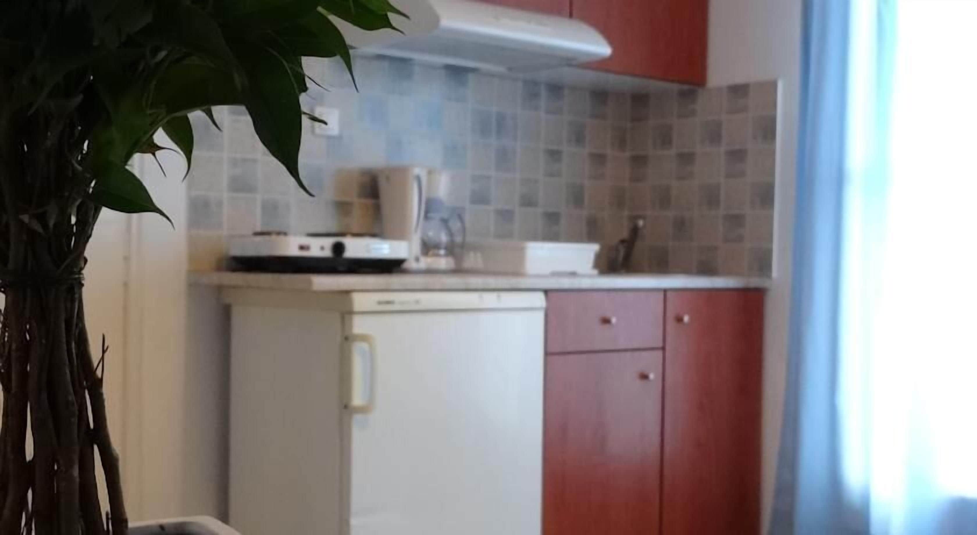 A compact kitchen with a white refrigerator, a coffee maker, and a microwave on the countertop.