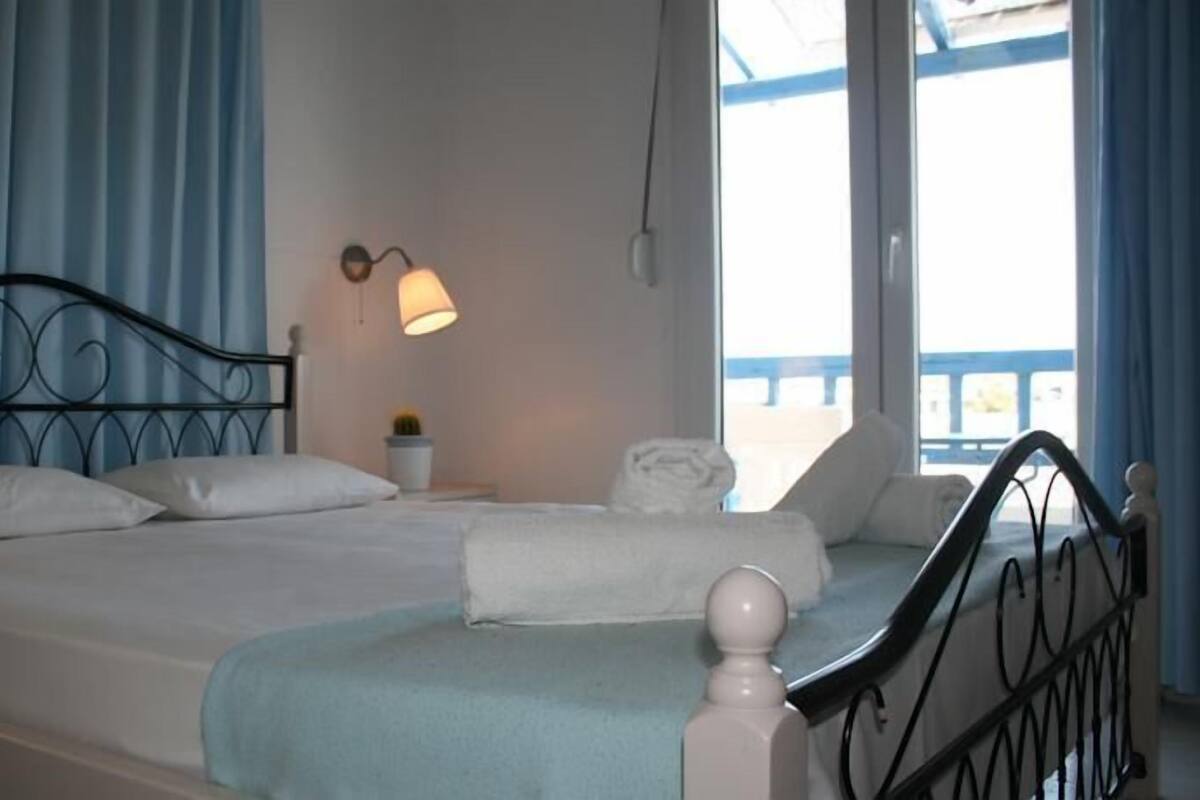 A bed with a metal frame, white bedding, and a blue curtain.