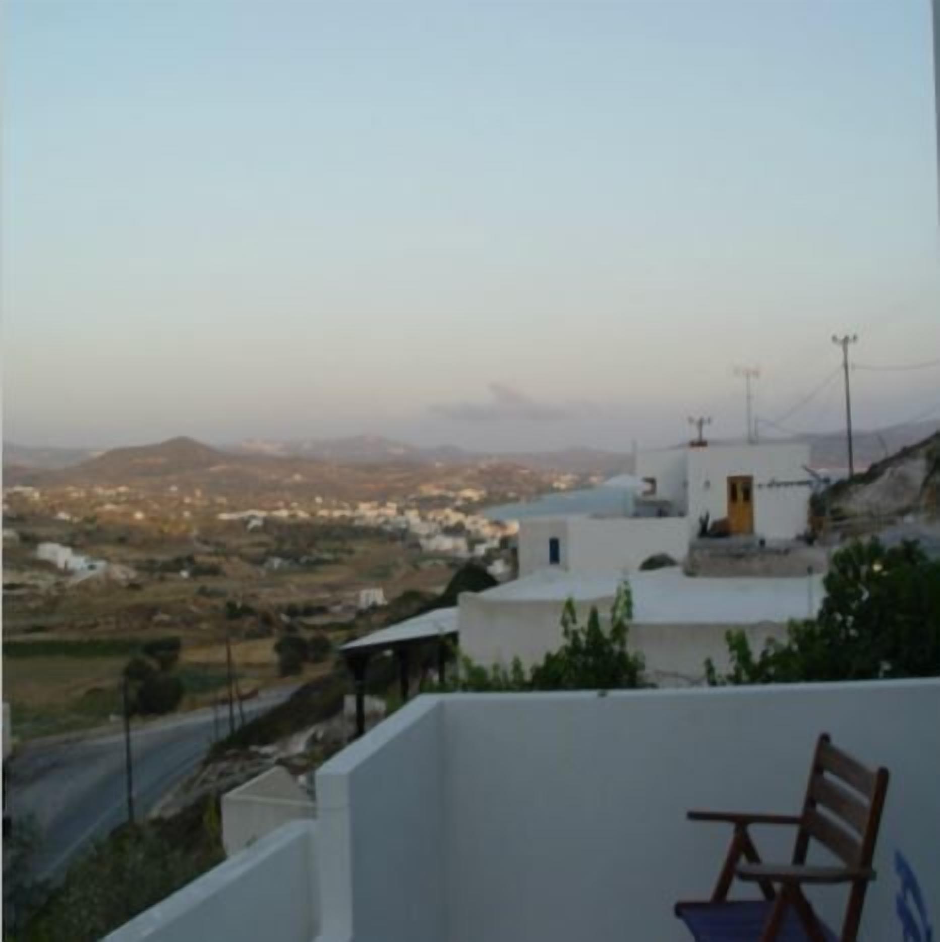 A view of a coastal town with white buildings and a chair on a balcony.