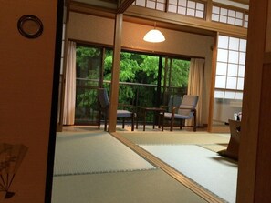 A traditional Japanese room with tatami flooring, sliding doors, and a view of greenery outside. - Okumizuma Onsen (Kaizuka)