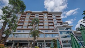 Een hotel met meerdere verdiepingen, balkons, terrasjes en een heldere lucht.