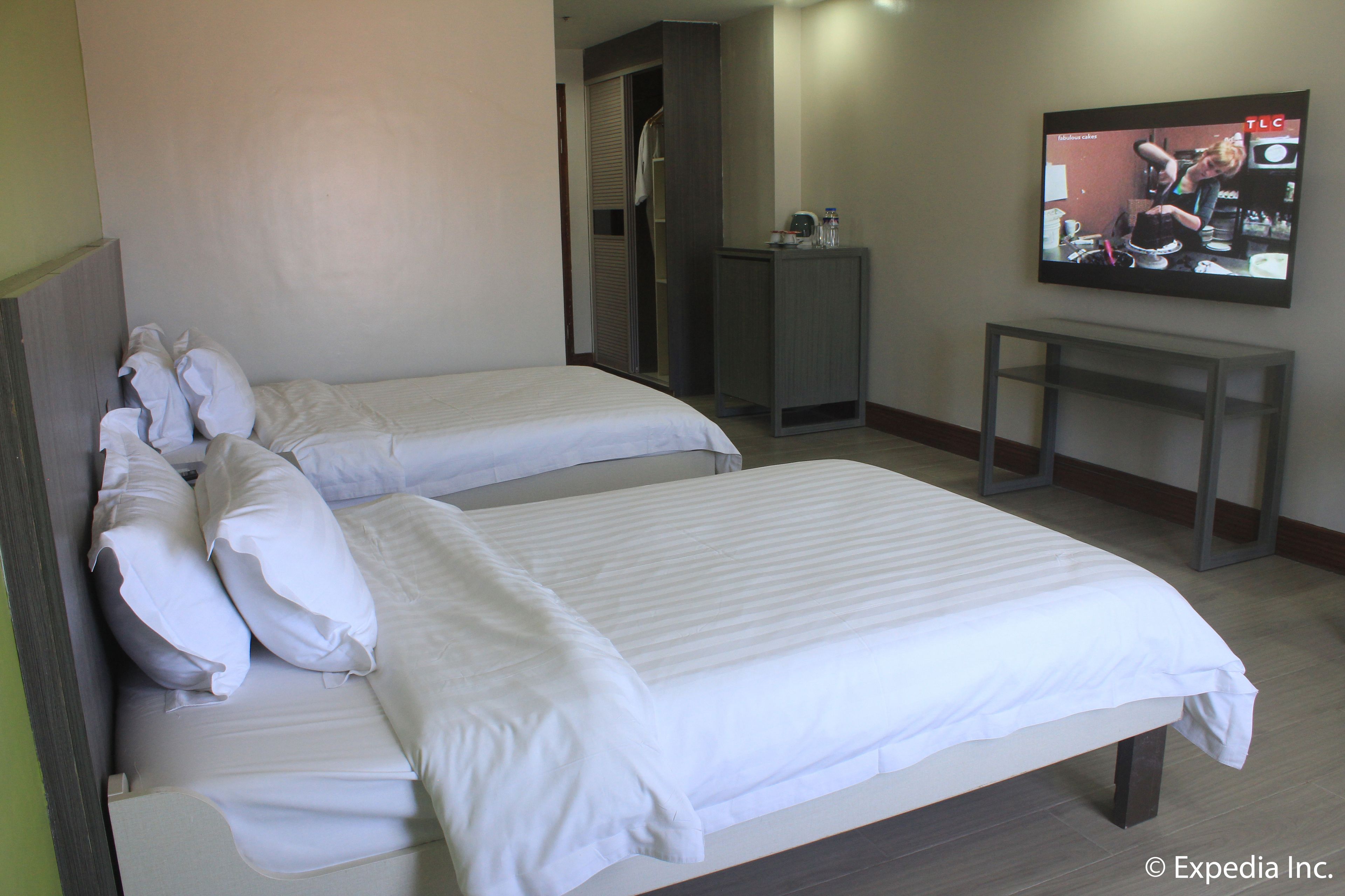 A hotel room with two beds, a TV, and a small desk.