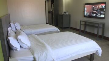 A hotel room with two beds, a TV, and a small desk.