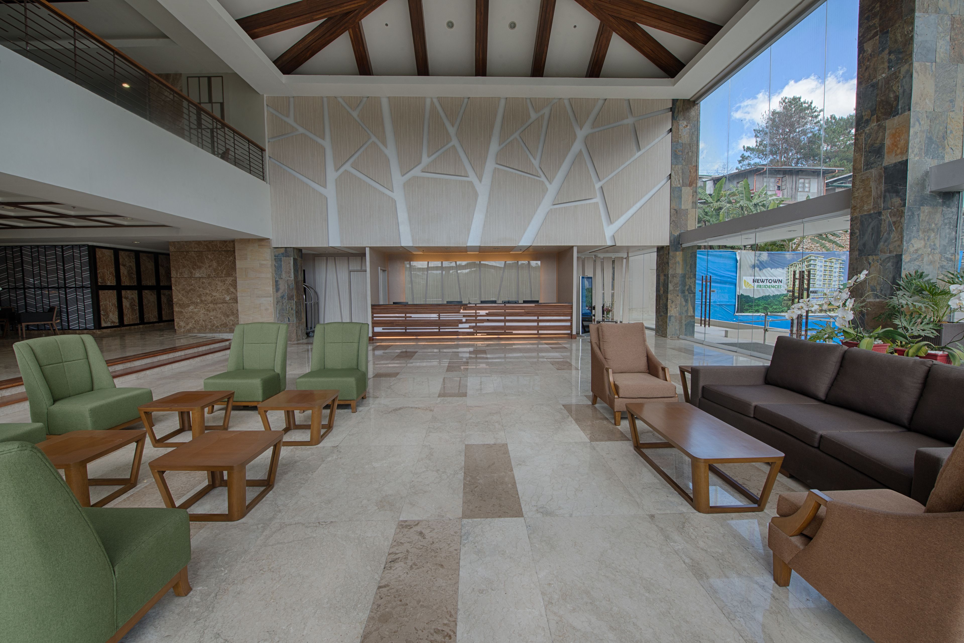 A spacious lobby with a high ceiling, modern furniture, and large windows offering views of the outside.