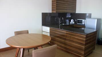 A modern kitchen with a central island, built-in appliances, and a round dining table with chairs.