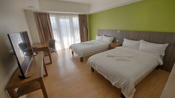 A hotel room with two beds, a desk with a chair, a television, and a window with curtains.